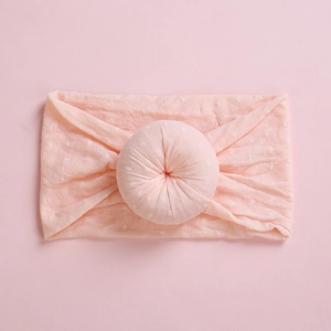 Close-up of baby headband with a donut knot in soft pink fabric and dot texture