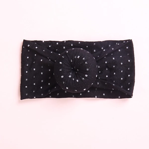 Detail of baby headband featuring soft black fabric with silver grid and donut knot