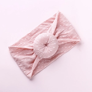 Close-up of pink baby headband with white polka dots and donut knot design details