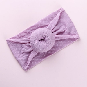 Detail of soft purple donut-style baby headband featuring a white polka dot pattern design