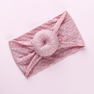 Detail of pink soft elastic baby headband with white polka dots and donut knot
