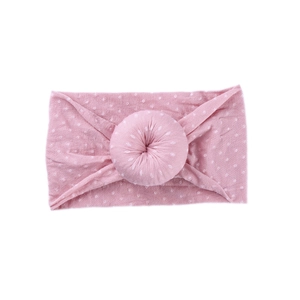 Pink baby headband with white polka dots and a donut-shaped knot on a clean white background