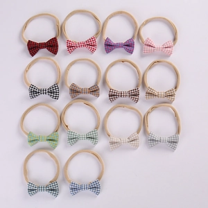 Flat lay of 14 colorful plaid bow baby headbands made of soft elastic nylon fabric