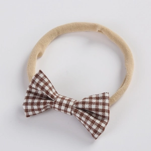 Detail of baby headband featuring brown and white plaid bow on soft nylon elastic