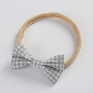 Close-up of baby headband with grey plaid bow and soft beige nylon elastic band