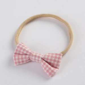 Detailed close-up of baby headband with a pink and white gingham bow on a soft elastic band