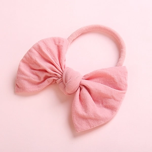 Close-up of soft pink knitted baby headband featuring a large decorative bow