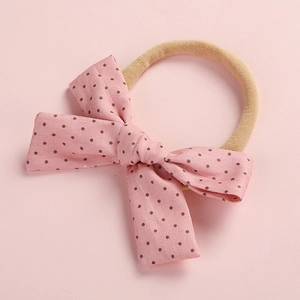 Dettaglio del fiocco in cotone a pois rosa su una fascia elastica in nylon per neonati