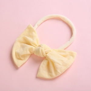 Soft nylon yellow bow headband for baby girls on a warm pink background for photography