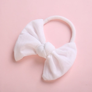 Detail shot of soft white fabric bow on elastic nylon headband for infant girls