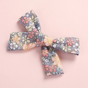 Close-up of the floral cotton bow hair clip showing detailed fabric texture and patterns