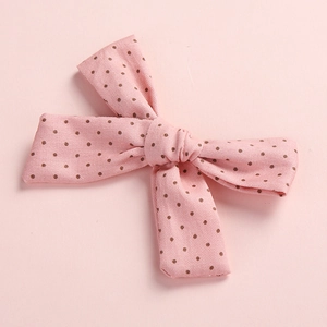 Close-up detail of a pink polka dot cotton bow hair clip for young girls and babies