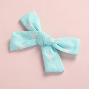 Close-up of light blue cotton bow hair clip with white star print on pink background