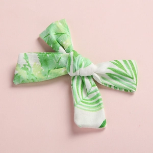 Detail of cotton bow hair clip featuring tropical green leaf print on pink background