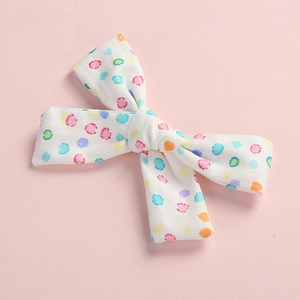 Detail of colorful polka dot pattern on cotton bow clip with pink backdrop