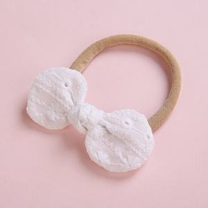 Bandeau bébé doux avec nœud papillon en dentelle brodée blanche sur fond rose pâle