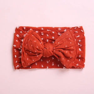 Bandeau souple rouge brique pour bébé avec grand nœud à pois et design sans couture