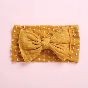 Détail du bandeau jaune pour bébé avec pois blancs et un grand nœud souple