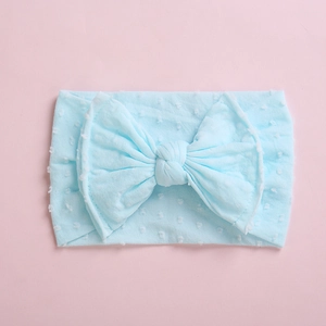 Gros plan du bandeau bébé bleu clair à pois 3D avec un grand nœud en tissu ultra doux