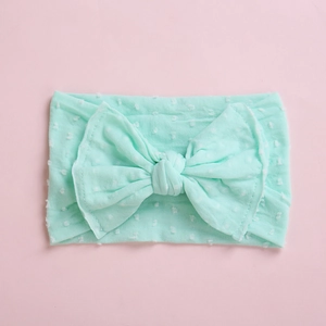 Détail du bandeau bébé vert menthe avec texture jacquard à pois doux et grand nœud