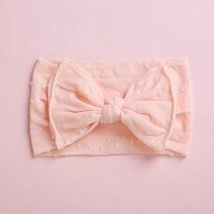 Détail macro du tissu à pois rose doux sur un bandeau à nœud pour bébé