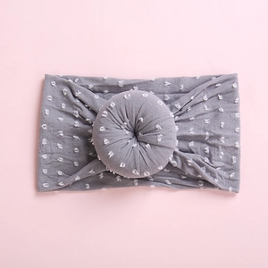 Detalle de una diadema gris para bebé con lunares blancos y un nudo redondo al centro