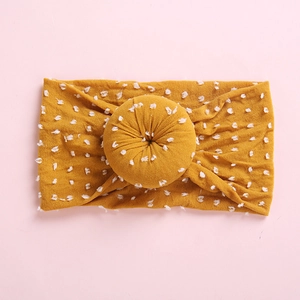 Detalle de diadema para bebé en nailon jengibre con lunares 3D blancos y nudo de donut