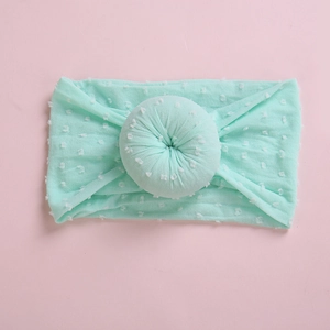 Primer plano de diadema para bebé en color verde menta con lunares y nudo de dónut