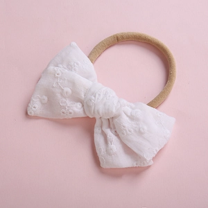 Bandeau bébé en dentelle blanche brodée avec bandeau en nylon élastique sur fond rose