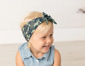 Close-up of a baby girl wearing a camouflage bow headband in navy and olive green tones