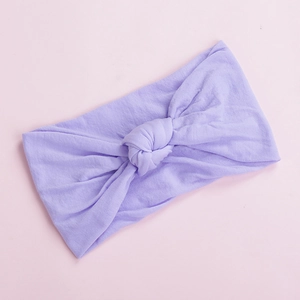 Detailed view of the soft lilac knotted nylon headband on a pale pink surface