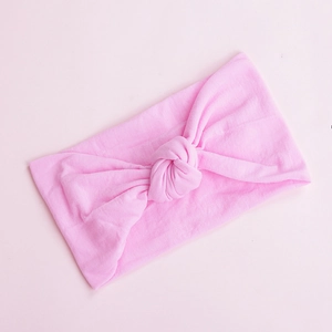 Macro detail of soft pink nylon baby headband featuring a stylish handcrafted central knot