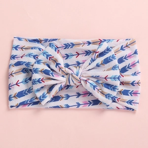 Detail view of baby bow headband with multi-color arrow print on soft white knit fabric