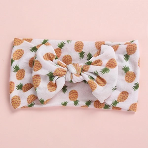 Detailed view of baby headband featuring yellow pineapple patterns and a large bow tie