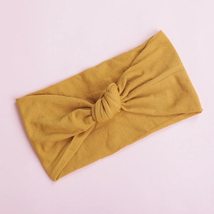 Detailed texture of ginger yellow soft nylon baby headband with a knotted bow design