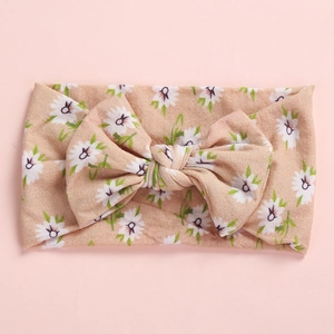 Detail of baby soft floral headband with large bow and white daisy print on pink fabric