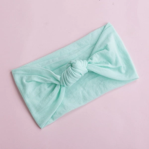Close-up of soft mint green nylon baby headband with a decorative knot detail