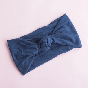 Detail of soft navy blue nylon headband with a classic knot design on a pink background