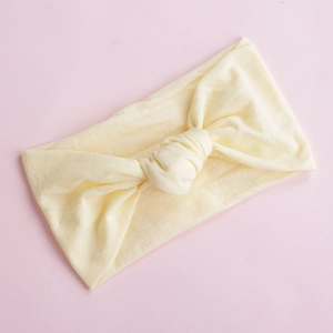 Detail of soft cream yellow nylon headband with twisted knot on a pink background