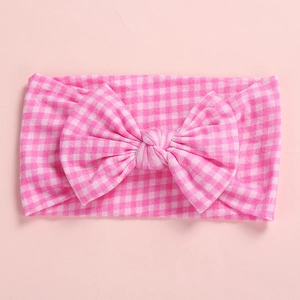 Detail of pink gingham bow headband for infants made of soft and elastic knit fabric