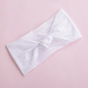 Close-up of soft white nylon baby headband with a wide design and decorative center knot