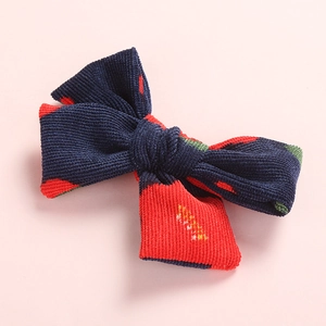 Detailed texture of navy blue corduroy hair clip with red polka dots and bow design