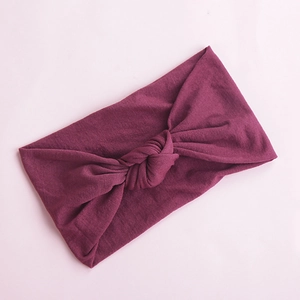Detailed texture of purple knotted wide nylon headband for babies on pink background