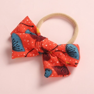 Floral red corduroy bow baby headband with elastic nylon band on pink background
