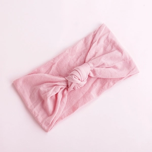 Close-up of soft pink nylon baby headband with a decorative hand-tied knot detail