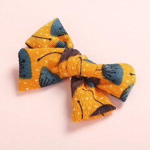 Orange floral corduroy bow hair clip with navy flower patterns on pink background