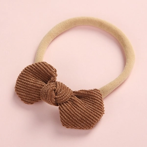 Détail d'un nœud en velours côtelé marron sur un bandeau en nylon beige pour bébé