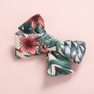 Detail of floral printed corduroy hair clip with tropical red flowers and green palm leaves