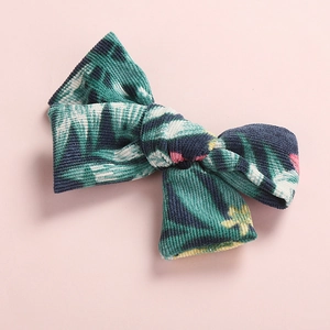 Detailed macro view of tropical floral print corduroy fabric on a girls' bow hair clip
