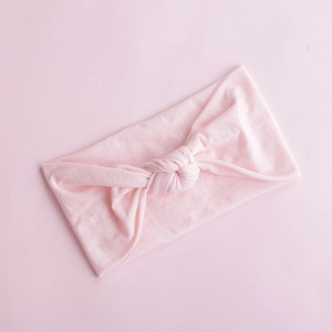 Detailed view of a soft pale pink knotted nylon baby headband with knitted texture